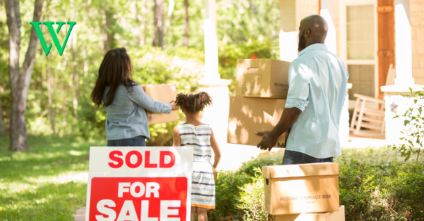 Family holding boxes moving into new home